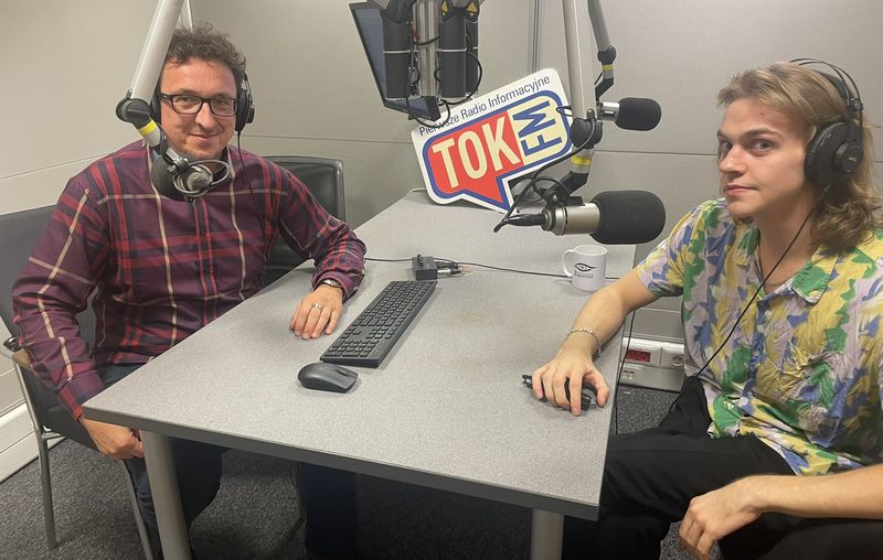 Jan Niziński w słuchawkach przy mikrofonie w studiu TOK FM, obok prowadzący audycję